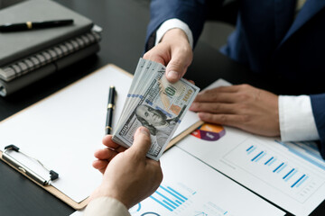 businessman giving money, dollar currency, to his partner in office - loan, payment and bribery concept