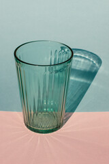 Green drinking glass with harsh shadow on colored background.