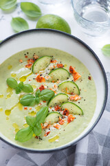 Bowl of cold gazpacho made of cucumbers and green basil, vertical shot, closeup, selective focus