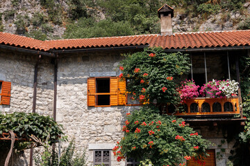 Fototapeta na wymiar stone old building with a tiled roof in Europe with flowering shrubs in summer