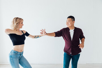 a man and a woman dance bachata music in a white room