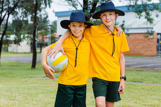 Two Australian kids in school uniform with a ball