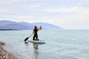 Rear view on redhead Young woman sailing on beautiful calm sea with crystal clear water. The concept of summer holidays vacation travel, relax, active and healthy life in harmony with nature.