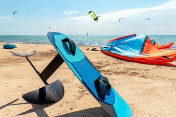 Close-up hydrofoil surf board and kite equipment on sand beach shore watersport spot on bright...