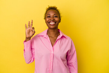 Young african american woman isolated on yellow background cheerful and confident showing ok...
