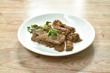 fried slice pork meat and liver with garlic couple pepper topping parsley on plate