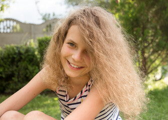 Naklejka premium Portrait of a charming smiling girl 12 years old in the park outdoors. Enjoy the moment, positive intention, joyful summer mood