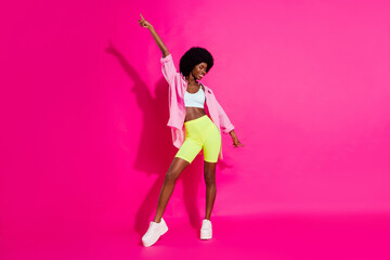 Photo of adorable pretty dark skin lady wear casual shirt pointing finger dancing smiling isolated pink color background