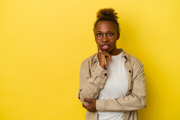 Young african american woman isolated on yellow background looking sideways with doubtful and skeptical expression.