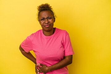 Young african american woman isolated on yellow background having a liver pain, stomach ache.