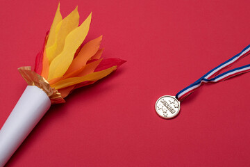 Torch made of paper and plastic medal on red background