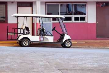 The golf cart is parked near the office part for the electric power charger. © trainman111