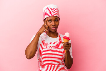 Young african american ice cream maker woman holding ice cream isolated on pink background pointing temple with finger, thinking, focused on a task.