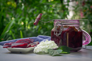 pickled beetroot in a jar stands on a table in nature pieces of pickled beet on a plate beetroot on...