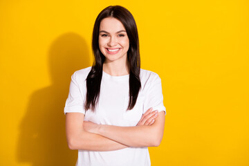 Photo of positive pretty young woman hold hands crossed confident isolated on shine yellow color background