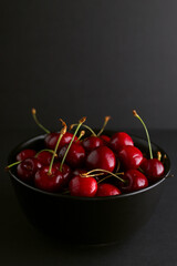 red sweet cherry in black plate on grey background
