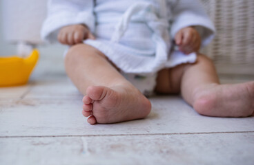 Obraz na płótnie Canvas close-up of the legs of a baby girl in a bathrobe on a laminate