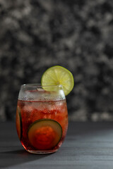 Bebida o Coctel con agua mineral, hielos y pepinos en rodajas sobre una mesa negra