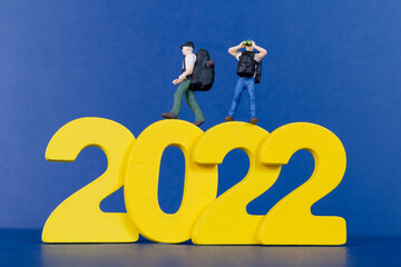 Miniature people backpacker standing on wooden number 2022 , Happy new year concept