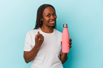 Young african american woman holding canteen isolated on blue background pointing with finger at you as if inviting come closer.