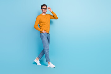 Full length profile side photo of young cheerful man happy positive smile go walk step confident isolated over blue color background