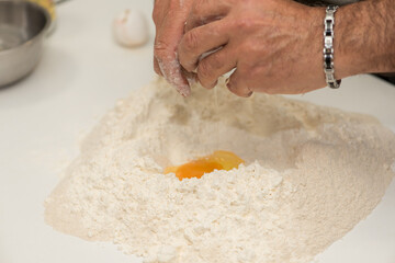 Flour and eggs. Hands kneading dough on board - flour and eggs. Selective focus. The concept of cooking, alibi, pizza with your own hands