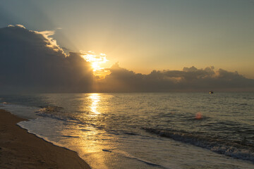 Golden hour, the sun's rays make their way through the clouds above the water surface © denfotoblog