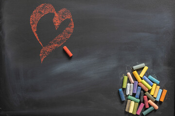 Blackboard with colored chalks and a drawn red heart