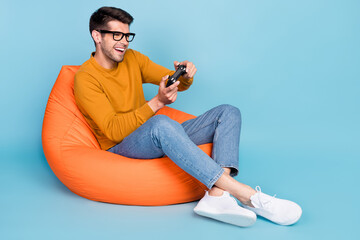 Portrait of attractive cheerful guy sitting in chair playing video game having fun free time...