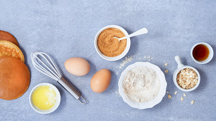 Banner food background. Ingredients for homemade oat pancake with whole grain oat, coconut sugar, vanilla syrup, organic eggs on light blue background. Healthy food recipe. Top view. Copy Space.