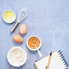 Fototapeta na wymiar Healthy Food Background, Ingredients for homemade oat pancake with whole grain oat, coconut sugar, vanilla syrup, organic eggs next to a white notebook in a pen on light blue background. Copy space.