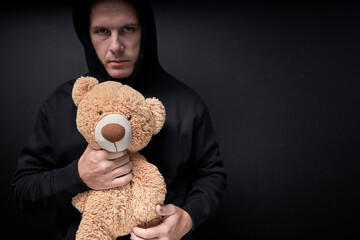 Man holding teddy in hands, toy is simulating child abuse, rape and kidnapping. Adult man in casual...