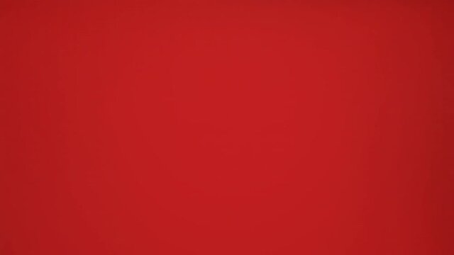 A cute finger puppet (in the shape of a frog) walking and moving over a red background, in a funny way.
