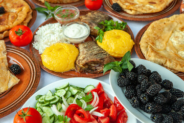 Homemade Romanian Food with grilled fish, polenta, pies, vegetables with red wine. Platter on camping.