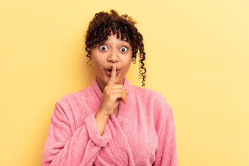 Young mixed race woman wearing a pink bathrobe isolated on pink background keeping a secret or asking for silence.