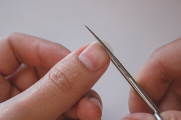 A person cuts his nails with small scissors. Men's manicure. A man cuts off a large overgrown nail