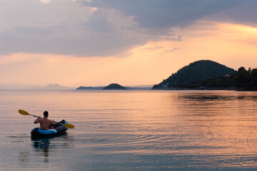 Naklejka na ściany i meble Man kayaks solo at sunset