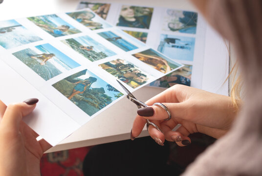 A woman cuts out photos with people in close-up. A girl uses scissors to cut printed polaroid photos for an album. A person holds a polaroid photo in his hands against the background of other photos.