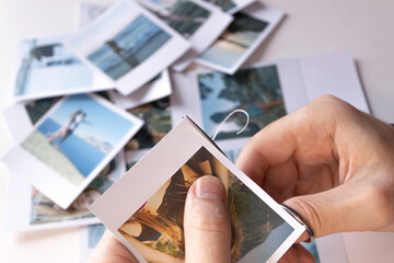 A man cuts out photos with people in close-up. A man uses scissors to cut printed polaroid photos...