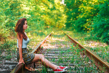 A young woman on an abandoned railway track in the forest.