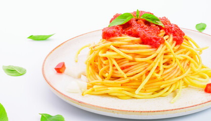 Close-up shot of spaghetti or pasta with tomato sauce and fresh green basil on a white plate with tomato isolated on a white background - top view