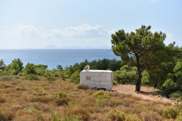 Old shabby fully autonomous caravan with satellite antenna and solar panels on roof -  downshifter hermit's dwelling is escaped from city on coast sea. Counterurbanization or deurbanization concept.