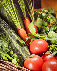 Selected focus, vertical, vegan composition with local, farm vegetables in a basket: tomatoes, cucumbers, zucchini, carrots, parsley, dill and basil. Sale of seasonal vegetables at the local market
