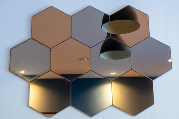 Hexagon-shaped mirrors line up on a white wall.