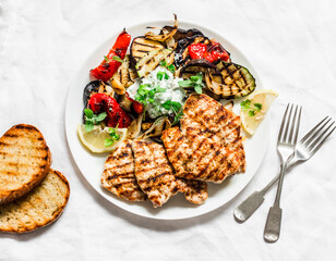 Delicious tapas barbecue set - grilled turkey, aubergine, zucchini, bell pepper with tzatziki sauce on a light background, top view