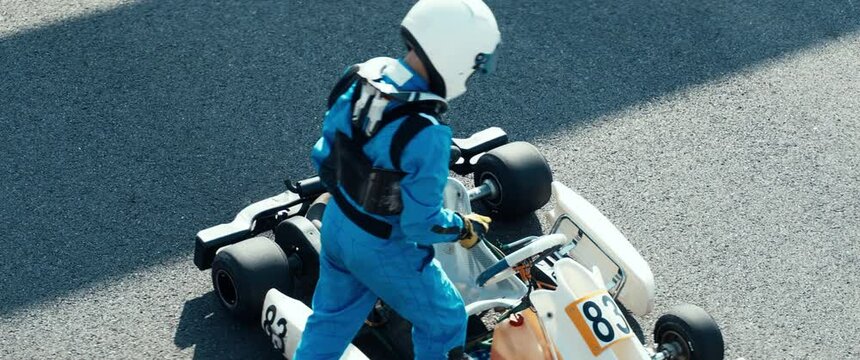 Teenager professional karting racer putting on protective gear on a race track. Shot with 2x anamorphic lens