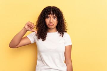 Young mixed race woman isolated on yellow background showing a dislike gesture, thumbs down. Disagreement concept.
