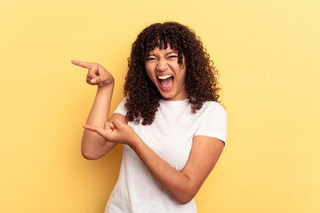 Young mixed race woman isolated on yellow background excited pointing with forefingers away.