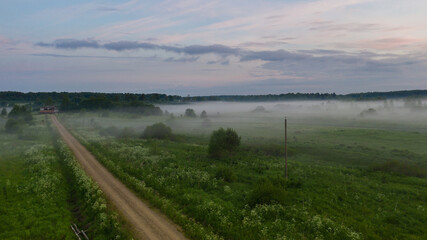 Fototapeta na wymiar Foggy sunrise over the Russian village. The early morning fog spread over the village.