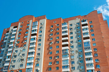 Multi-storey residential building with split systems and satellite dishes on the facade.
